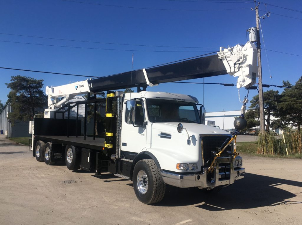 White, tri-axel truck crane with its rear-mounted telescopic boom lowered